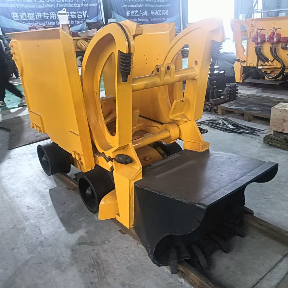 Yellow compact rail rock loader photographed in a workshop